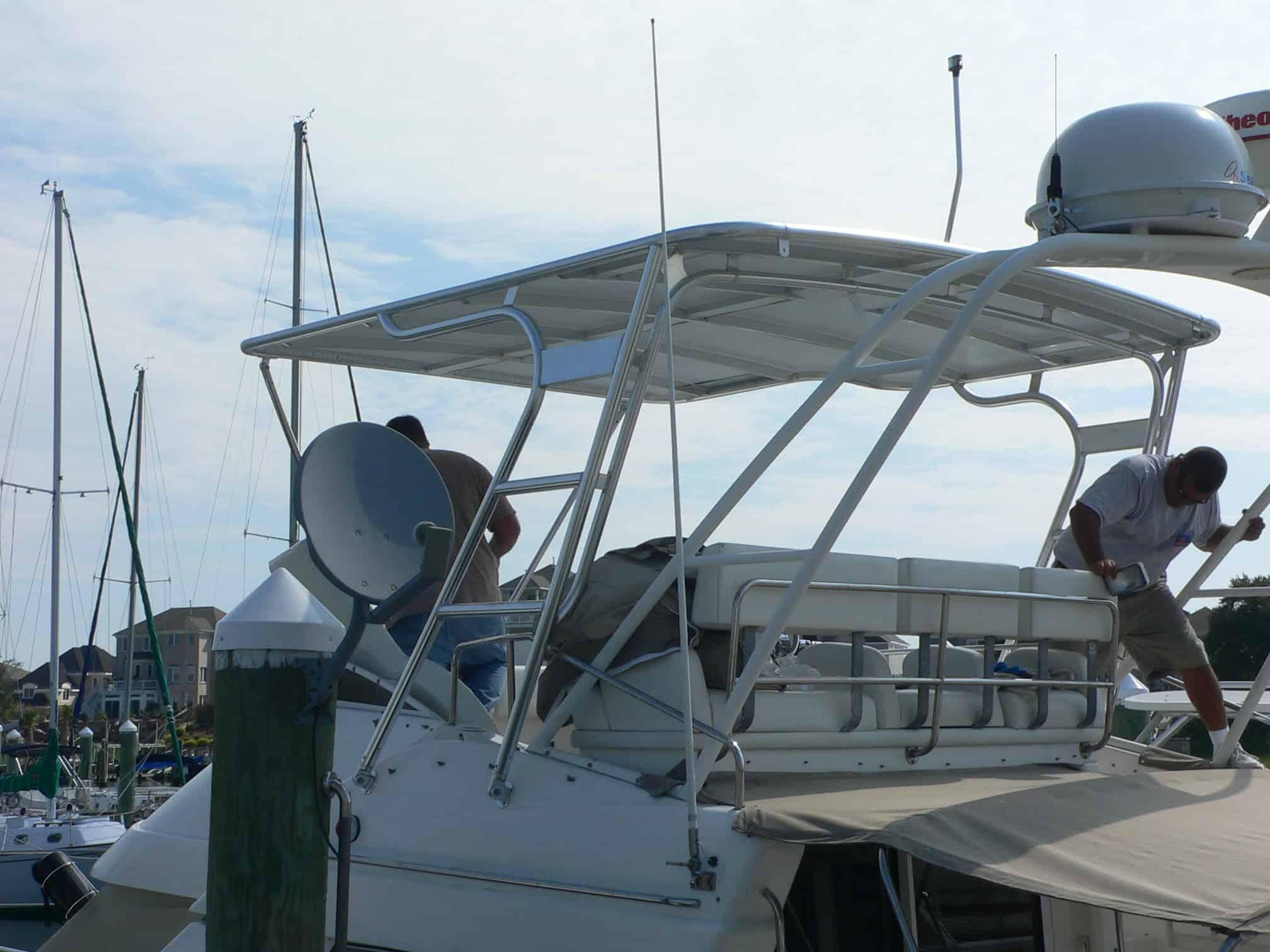 Atlantic Towers Top installed on a Silverton 351 Sedan showing two men working on the boat's upper deck railing and roof frame.