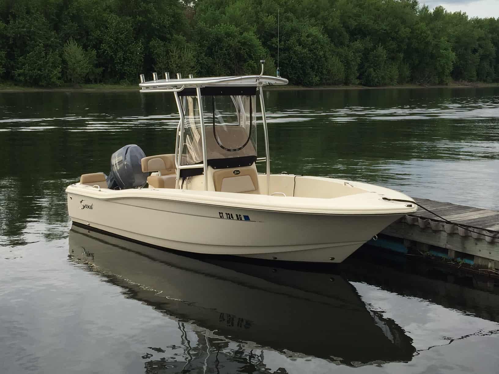 Atlantic Towers T-Top installed on a Scout boat, docked by a serene waterfront with green foliage in the background.