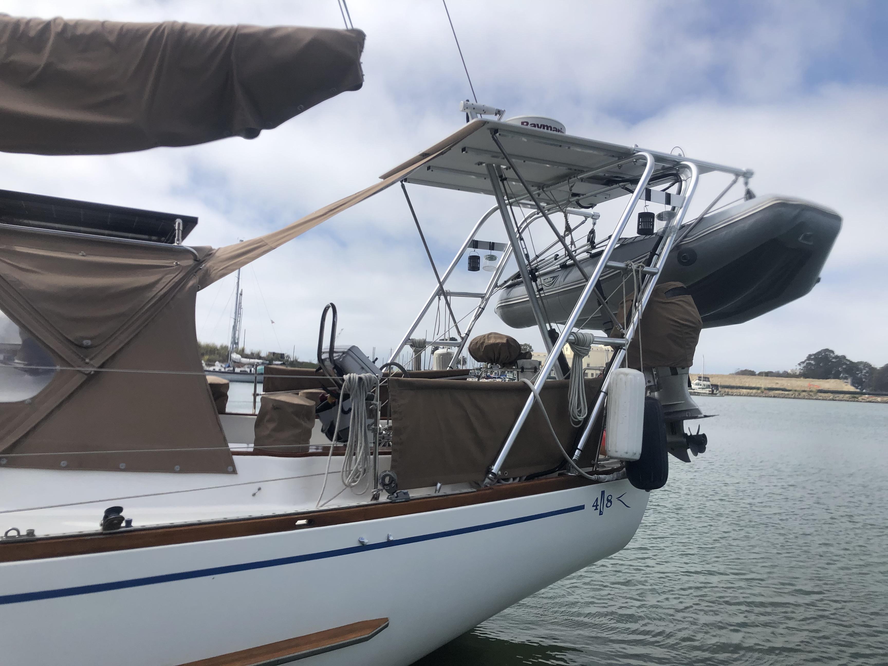 Atlantic Towers Arch installed on a boat with a dinghy and striped sail cover, docked in a harbor setting.