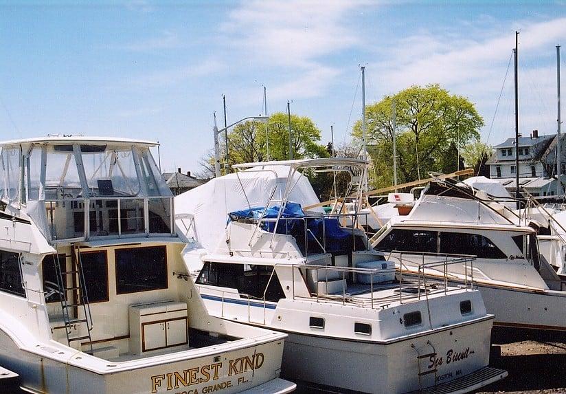 Mainship Double Cabin boat with installed Atlantic Towers Top parked in a marina with nearby boats and trees in the background.
