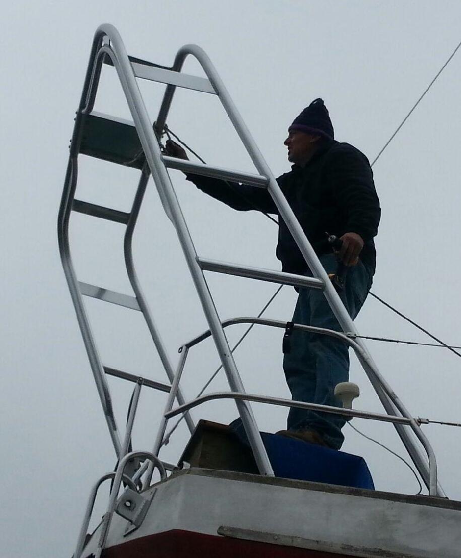 A person stands on the Atlantic Towers Arch, working on a boat under a cloudy sky.