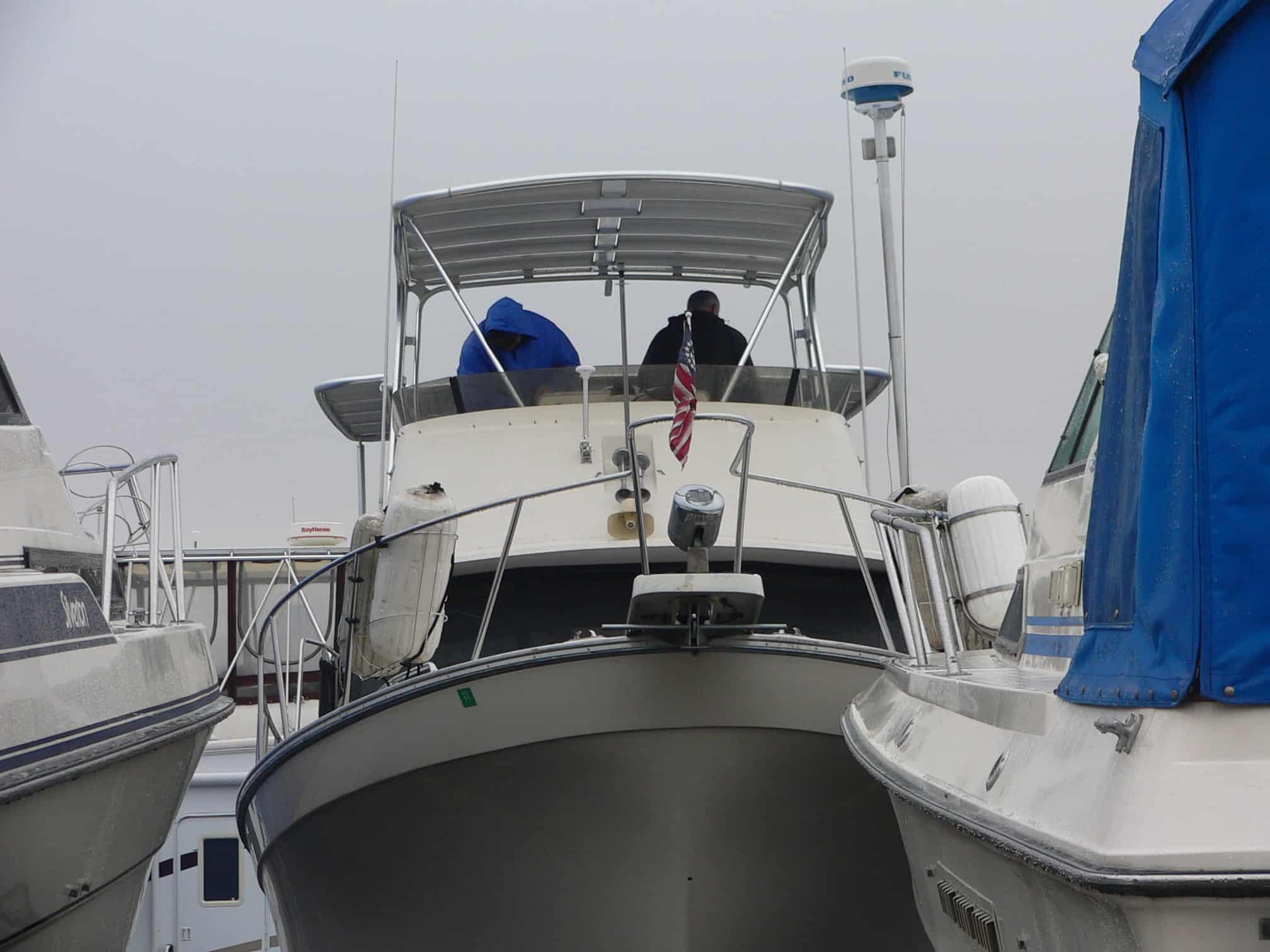 Front view of Mainship 36 Double Cabin boat with Atlantic Towers Top and two people on the deck in a marina.
