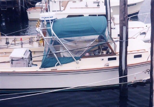 Fortier Boats 26 moored at a dock with an Atlantic Towers arch and green canvas cover over the helm area.