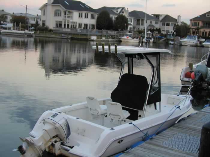 Wellcraft Center Console boat docked with Atlantic Towers T-Top installed, calm marina and houses in background