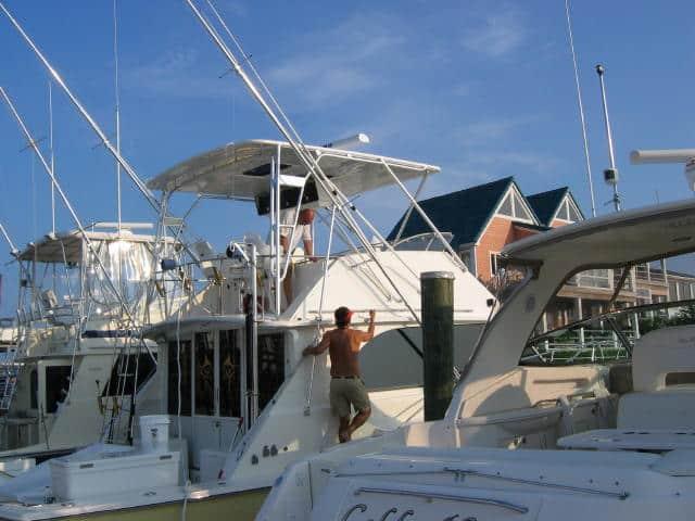 A man works on an Atlantic Towers Top installed on a Bertram 46.6 Convertible boat at a marina.